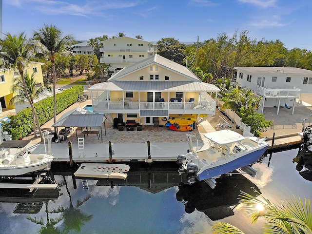 back of property with a patio area, a water view, and boat lift