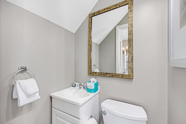 half bathroom with lofted ceiling, toilet, and vanity