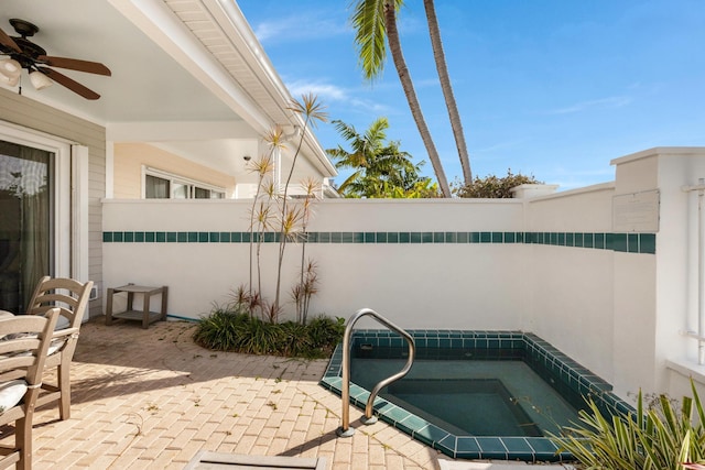view of patio / terrace with an in ground hot tub, a ceiling fan, and fence