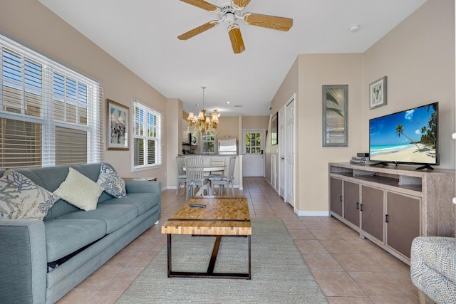 living area with light tile patterned floors, baseboards, and ceiling fan with notable chandelier