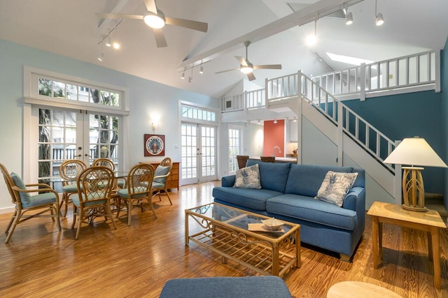 living room featuring ceiling fan, light hardwood / wood-style flooring, french doors, and beamed ceiling