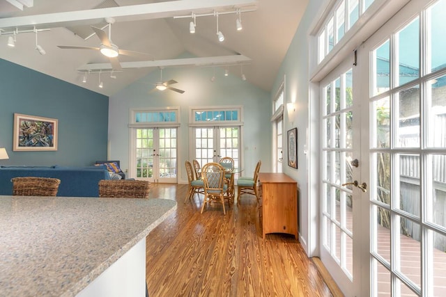 kitchen featuring high vaulted ceiling, hardwood / wood-style floors, light stone counters, and french doors