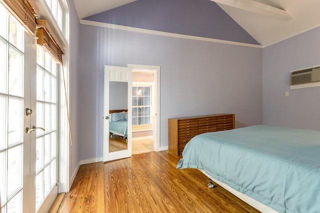 bedroom with multiple windows, a wall unit AC, french doors, and light wood-type flooring