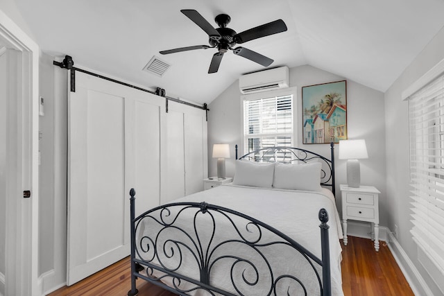 bedroom featuring lofted ceiling, a wall mounted AC, ceiling fan, a barn door, and hardwood / wood-style floors