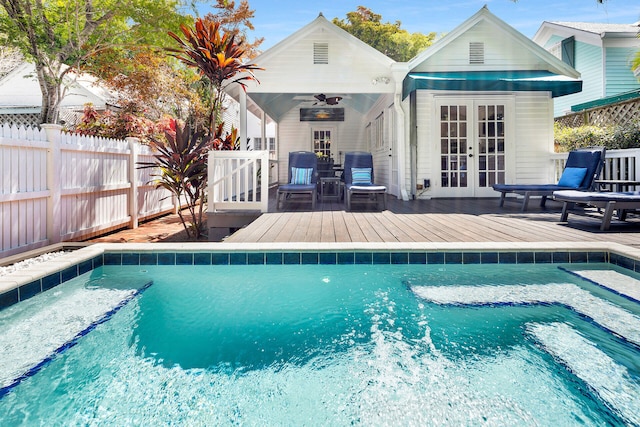 view of swimming pool with a deck, ceiling fan, and french doors