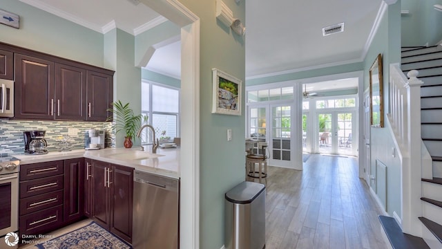 kitchen with french doors, sink, crown molding, stainless steel appliances, and decorative backsplash