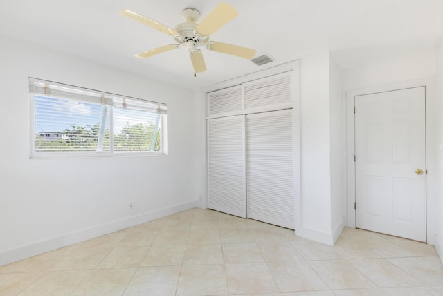 unfurnished bedroom with light tile patterned floors, ceiling fan, and a closet