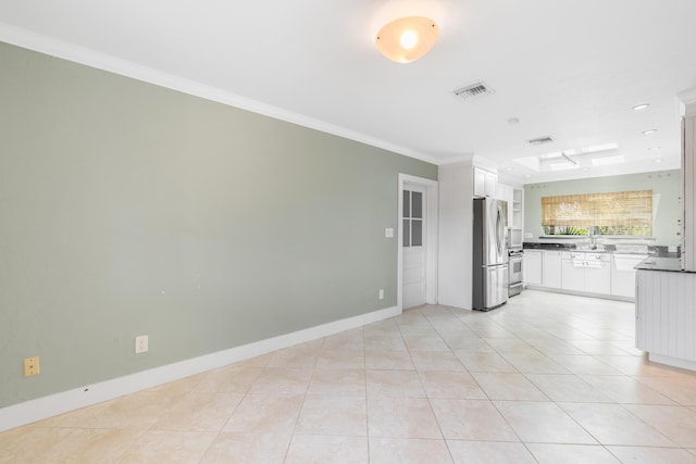 kitchen with light tile patterned flooring, appliances with stainless steel finishes, sink, white cabinets, and ornamental molding