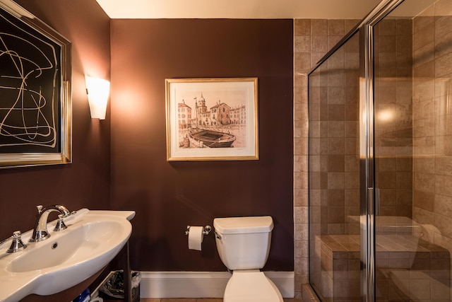 bathroom featuring an enclosed shower, sink, and toilet