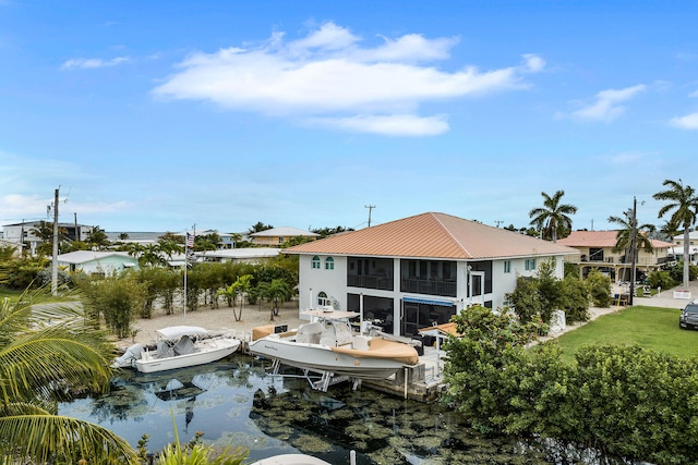 back of property featuring metal roof, a water view, and a sunroom