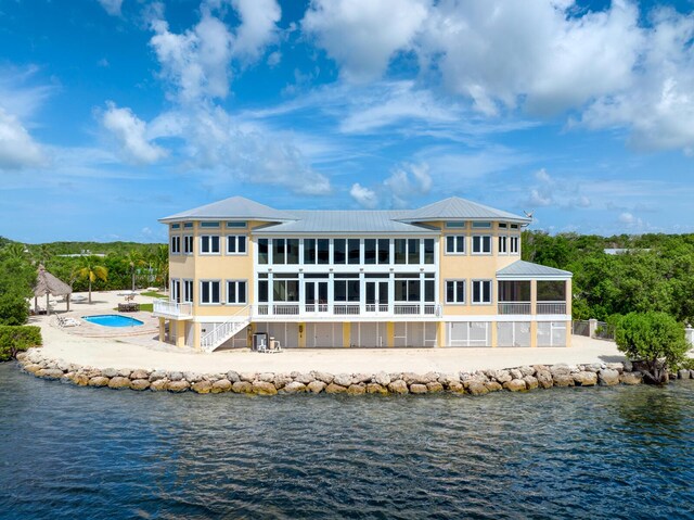 back of property with a sunroom and a water view