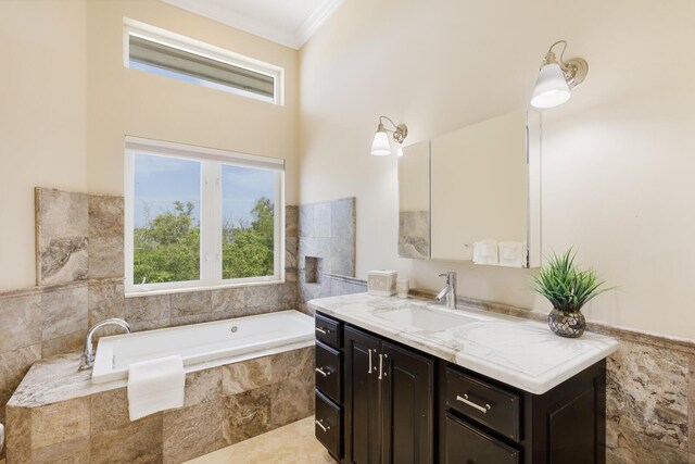 bathroom with tiled tub, vanity, and ornamental molding