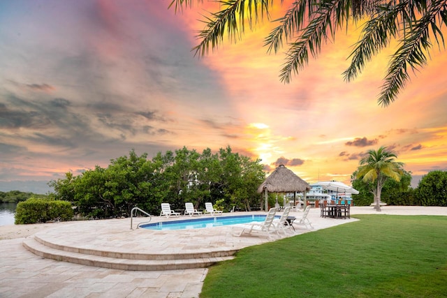 pool at dusk featuring a gazebo, a yard, and a patio area