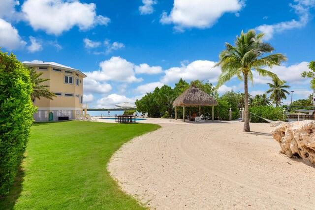 view of property's community featuring a gazebo, a water view, a pool, and a lawn