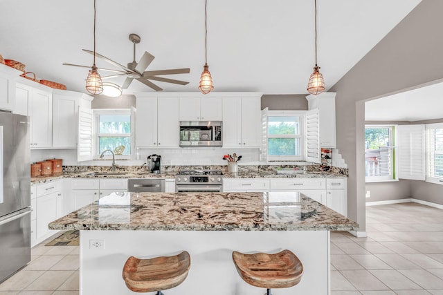 kitchen with sink, a breakfast bar area, appliances with stainless steel finishes, a kitchen island, and white cabinets