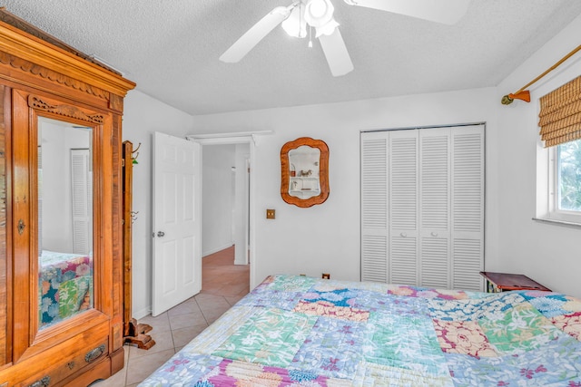 tiled bedroom with a textured ceiling, ceiling fan, and a closet