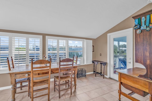 tiled dining space featuring vaulted ceiling