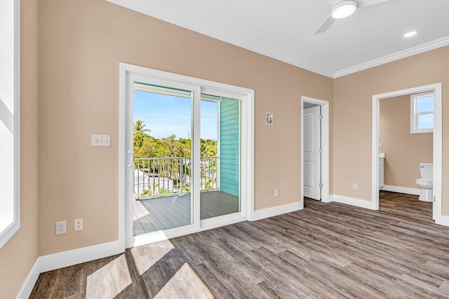 empty room featuring a ceiling fan, crown molding, baseboards, and wood finished floors