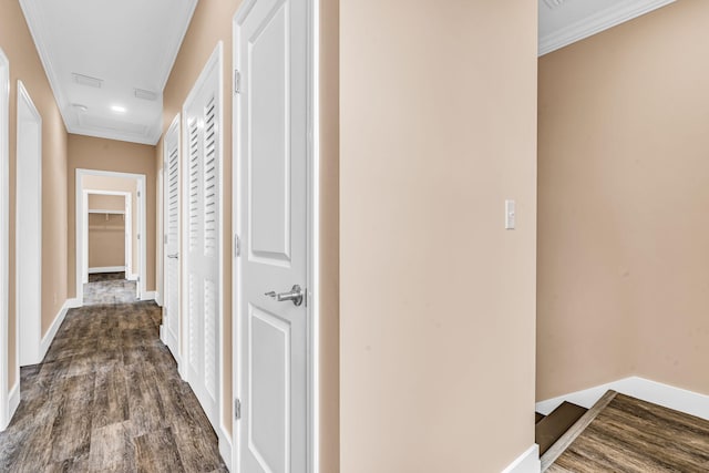 hall with dark wood-type flooring, ornamental molding, and baseboards