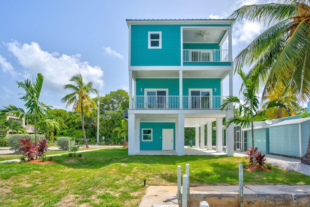 rear view of house featuring a balcony, a carport, and a lawn