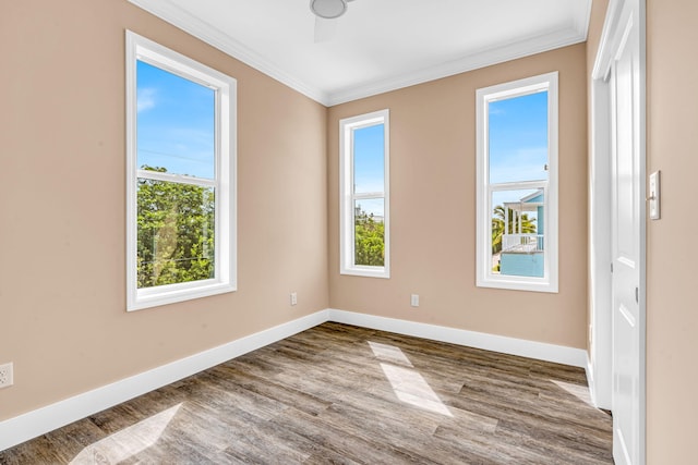 empty room featuring a wealth of natural light, baseboards, crown molding, and wood finished floors