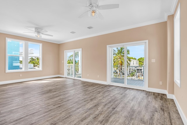 empty room featuring baseboards, wood finished floors, visible vents, and crown molding