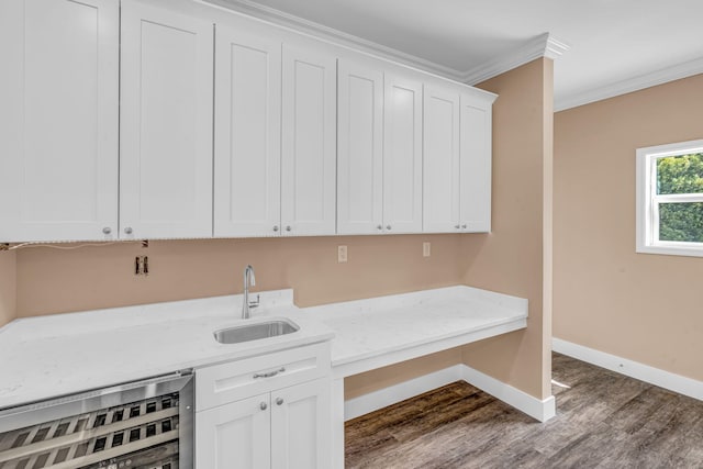 laundry area with baseboards, wine cooler, ornamental molding, dark wood-type flooring, and a sink