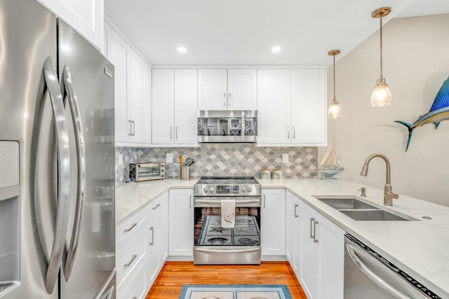kitchen featuring light wood finished floors, white cabinets, a sink, and stainless steel appliances