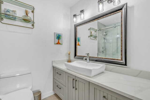 bathroom featuring baseboards, toilet, a stall shower, and vanity
