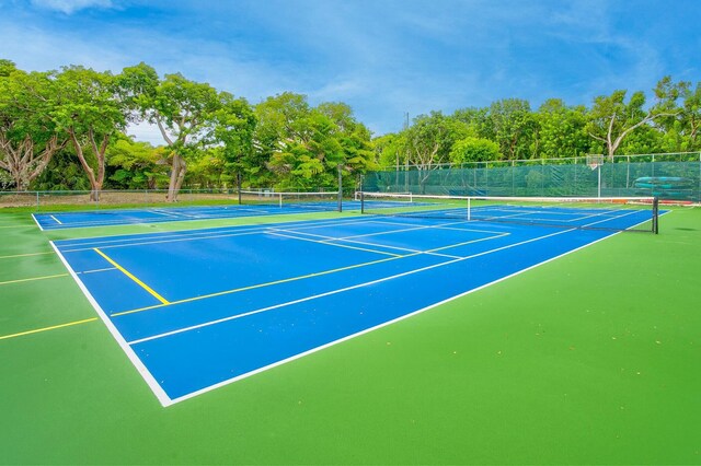 view of tennis court with community basketball court and fence