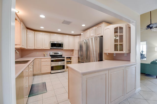 kitchen featuring sink, light tile patterned floors, kitchen peninsula, ceiling fan, and stainless steel appliances