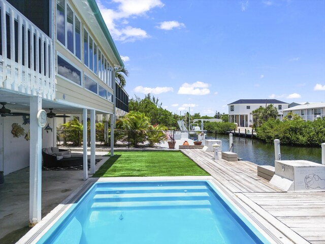 view of swimming pool featuring a deck with water view, a yard, and a patio area