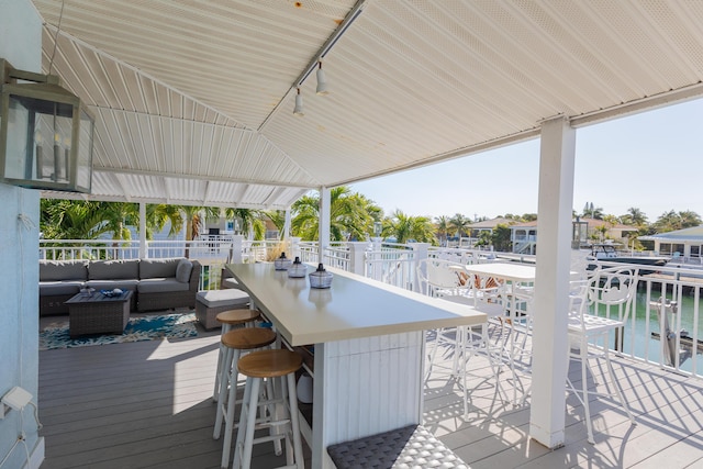 deck with a water view, outdoor lounge area, and a bar