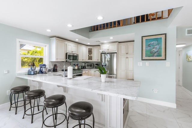 kitchen featuring appliances with stainless steel finishes, sink, a breakfast bar, and kitchen peninsula