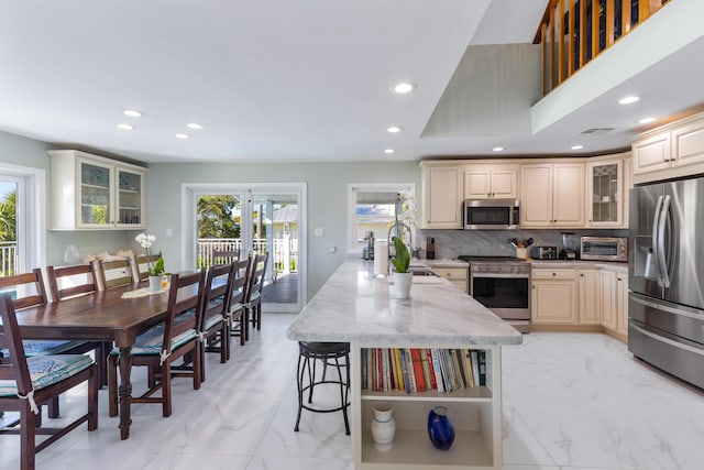 kitchen featuring backsplash, plenty of natural light, cream cabinetry, and appliances with stainless steel finishes