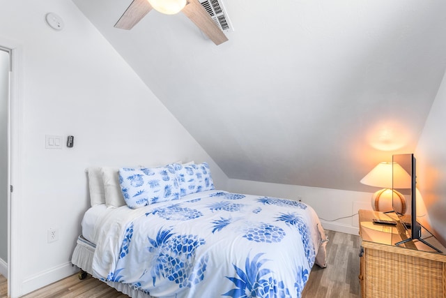 bedroom with ceiling fan, lofted ceiling, and wood-type flooring