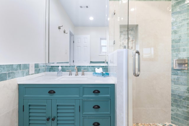 bathroom with vanity, tile walls, and a shower with shower door