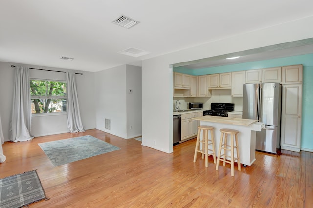 462 Sunset Dr, Key Largo, FL 33037 - kitchen featuring appliances with stainless steel finishes, light countertops, a kitchen island, a kitchen bar, and cream cabinetry