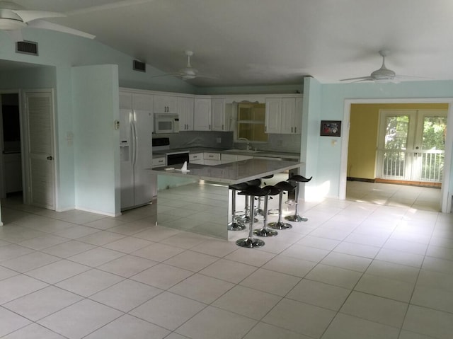 kitchen with ceiling fan, white appliances, a breakfast bar, and white cabinets