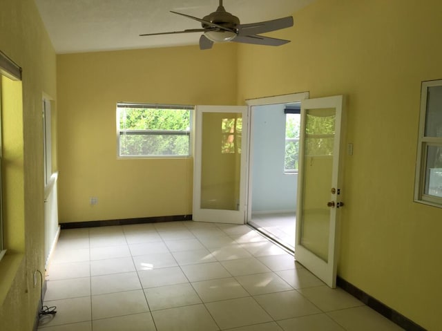 spare room with vaulted ceiling, light tile patterned flooring, ceiling fan, and french doors