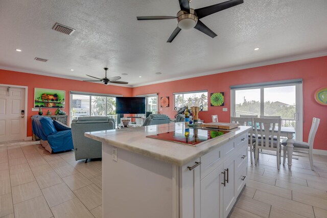 kitchen featuring white cabinetry, a center island, a textured ceiling, black electric cooktop, and ceiling fan