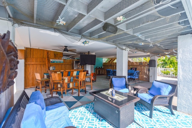 view of patio / terrace featuring a bar, ceiling fan, and an outdoor living space with a fire pit