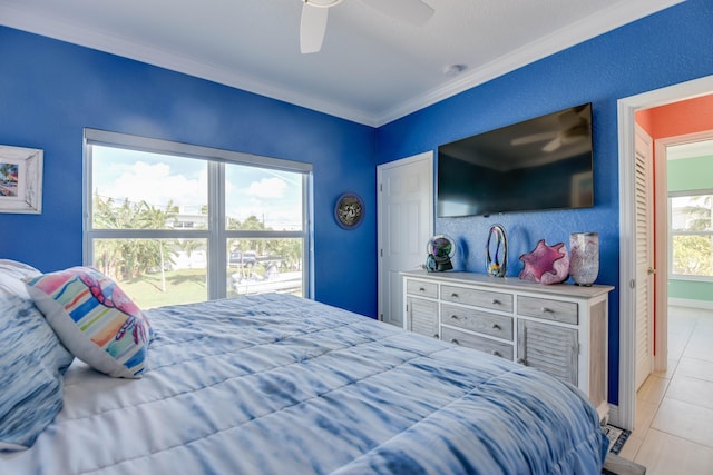 tiled bedroom with ornamental molding and ceiling fan