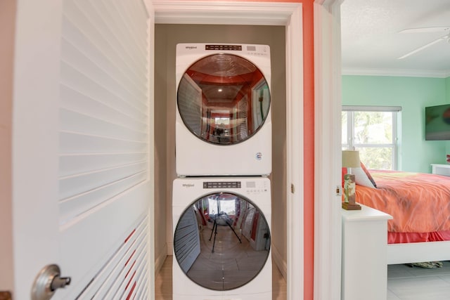 clothes washing area featuring crown molding, tile patterned floors, stacked washing maching and dryer, and a textured ceiling