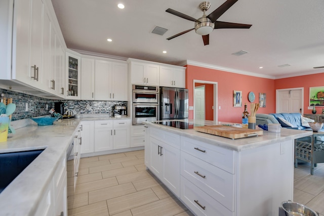 kitchen featuring a kitchen island, appliances with stainless steel finishes, tasteful backsplash, white cabinets, and crown molding