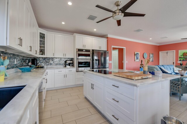 kitchen featuring a kitchen island, appliances with stainless steel finishes, tasteful backsplash, white cabinets, and crown molding