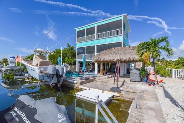 back of property featuring a water view, a patio, and a sunroom