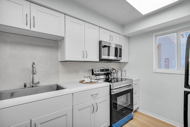 kitchen featuring stainless steel appliances, white cabinetry, sink, and light hardwood / wood-style floors