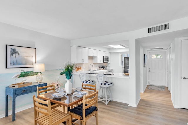 dining space featuring sink and light hardwood / wood-style flooring