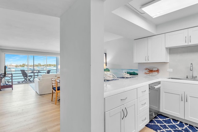 kitchen with light hardwood / wood-style floors, dishwasher, sink, and white cabinets